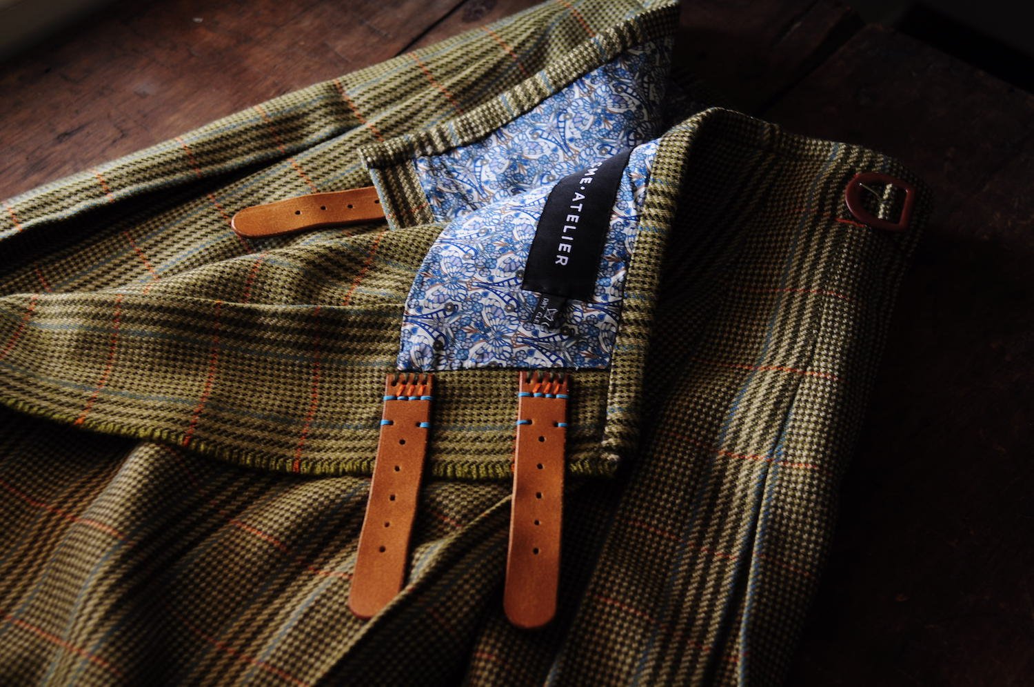 Shadowy image of a kilt partially unfolded on a wooden table.