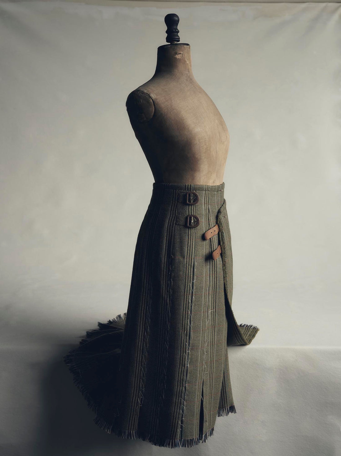 Image of a mannequin wearing a partially unbuttoned kilt placed in front of a white backdrop