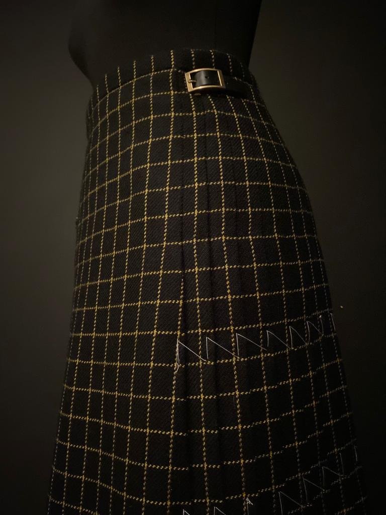 Image of a mannequin wearing a black and yellow kilt in front of a dark backdrop