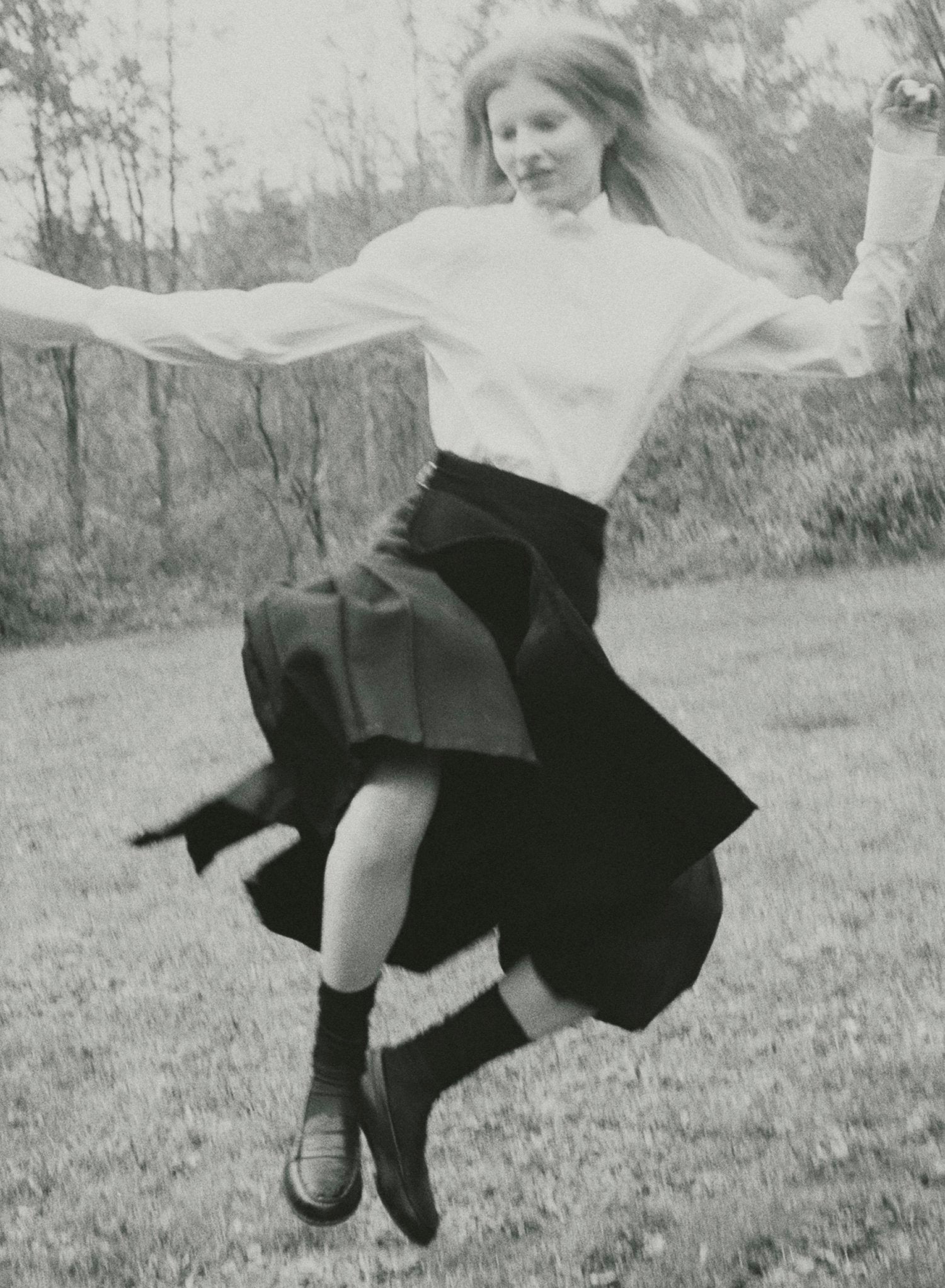 Black and white image of a model jumping mid-air wearing a kilt