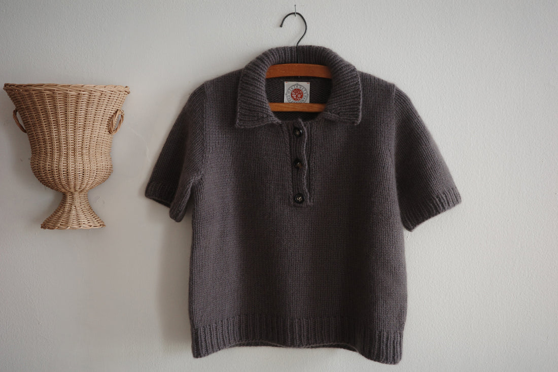 A taupe sweater hanging next to a wicker sconce on a wall