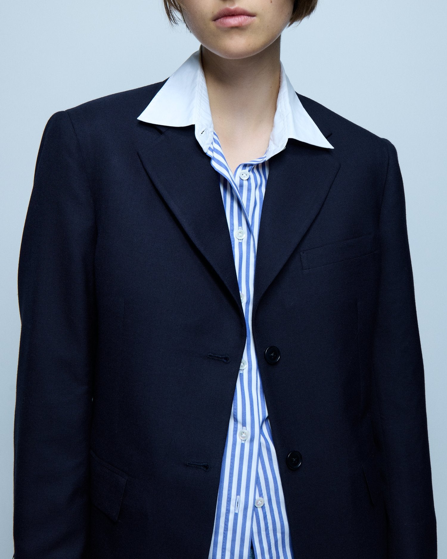 Close up image of a model wearing a blue blazer with a button down shirt underneath.