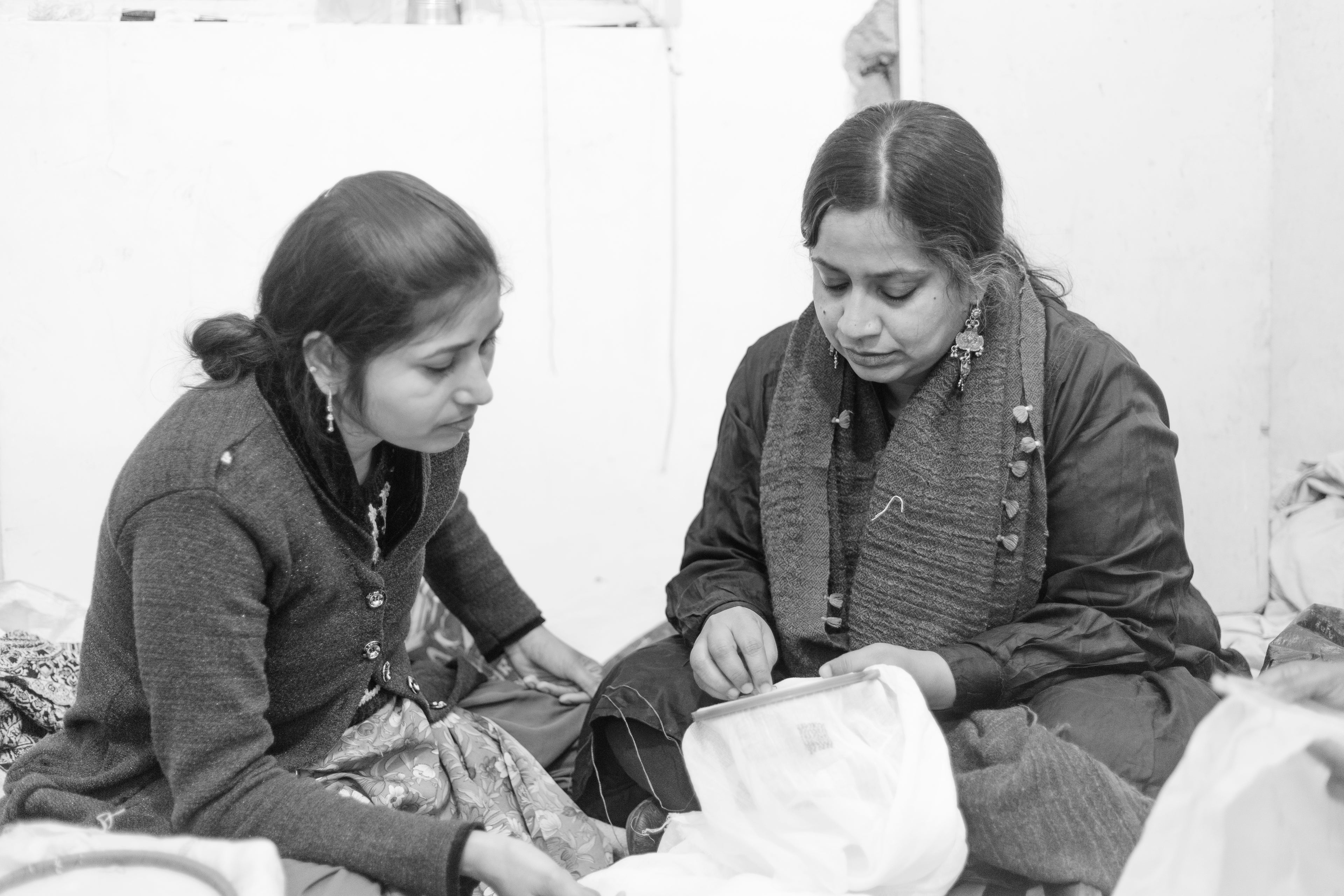 Two seated women working on hand embroidery.