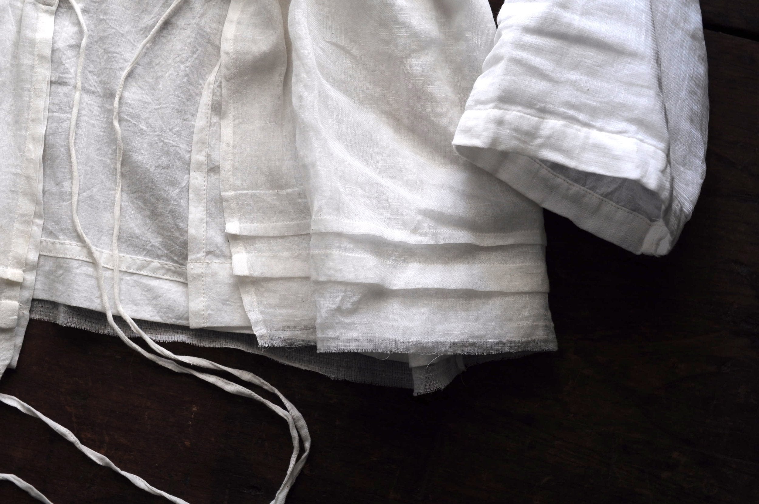 Close up image of the bottom hem a chemise top featuring french pleating and frayed edging.