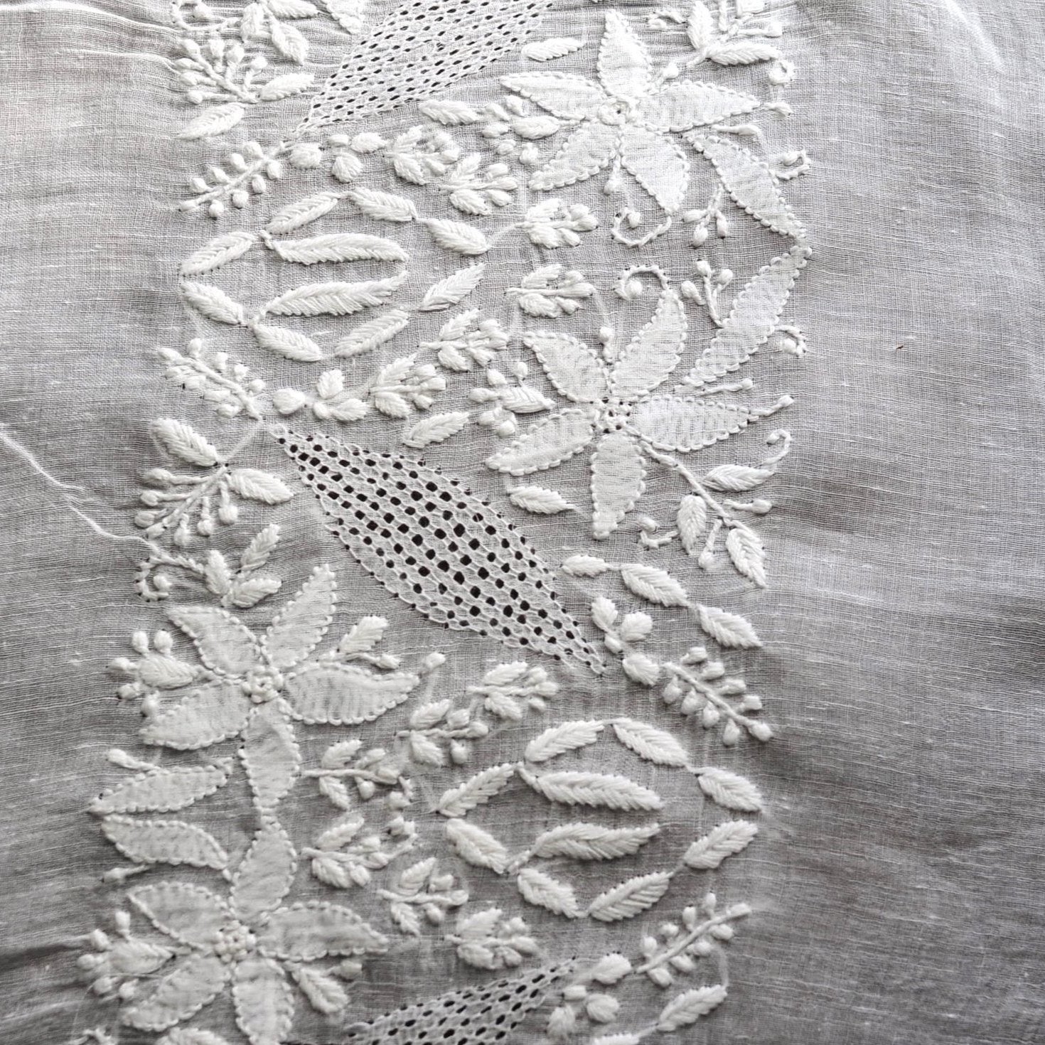 Close up image of white embroidered detailing on delicate white fabric.