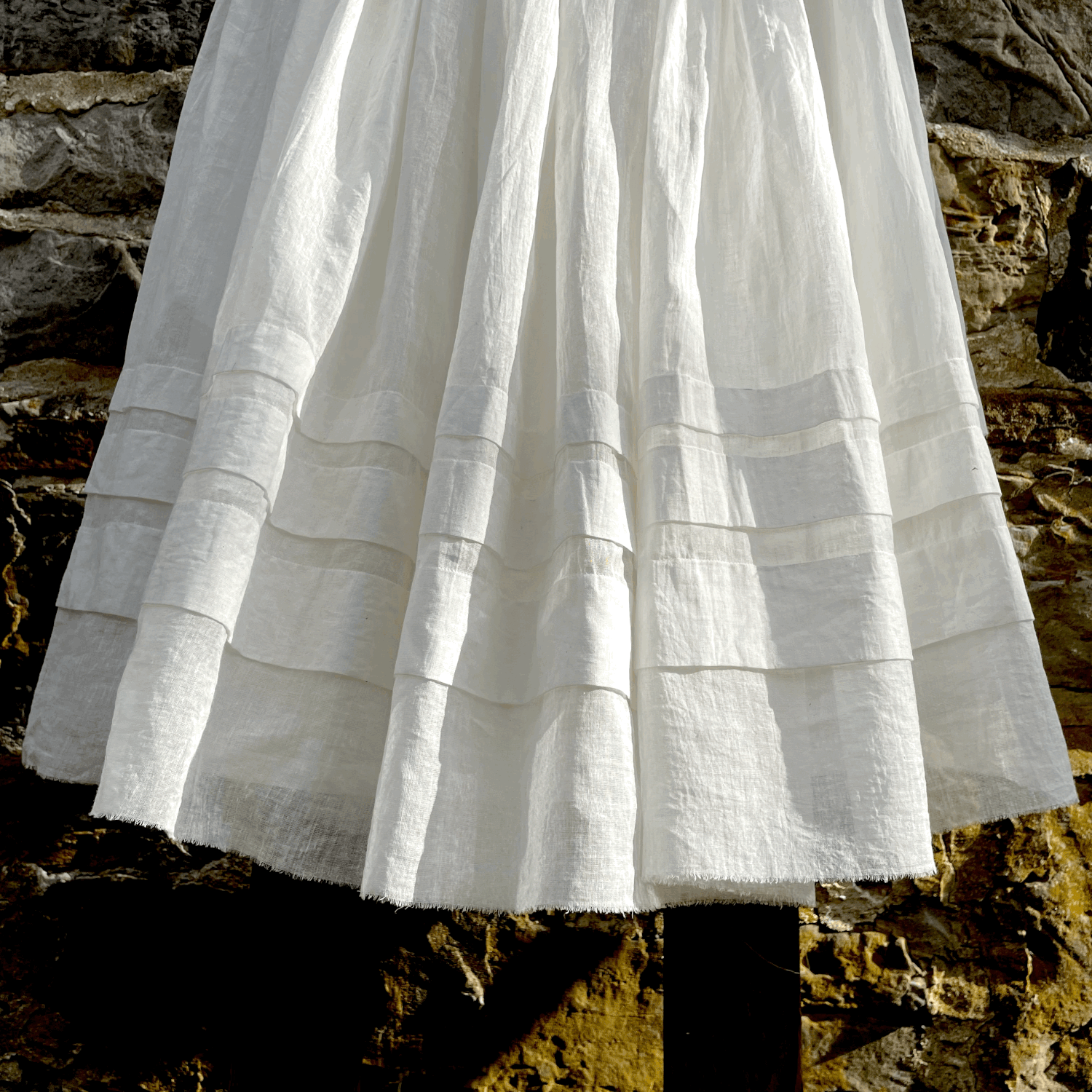 Close up image of the bottom of a white petticoat featuring french hem detailing and frayed edging.
