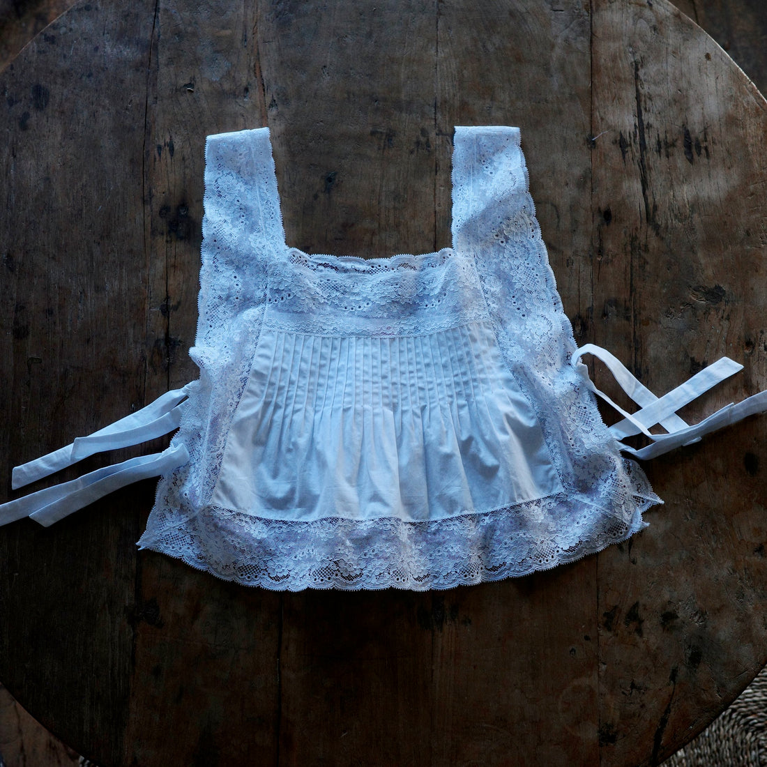 A shirt with shocking and lace detailing lays flat on top of a wooden table.