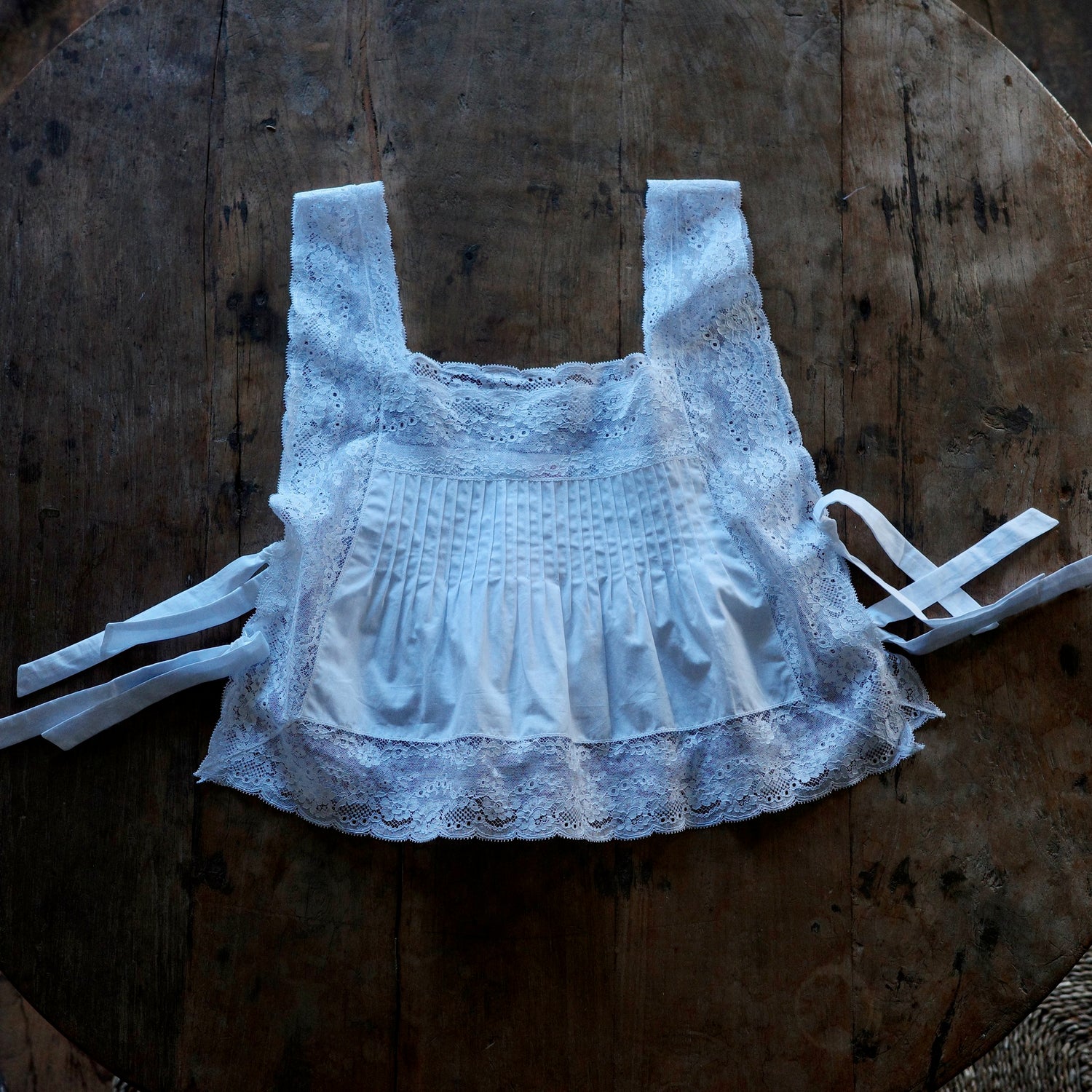 A shirt with shocking and lace detailing lays flat on top of a wooden table.