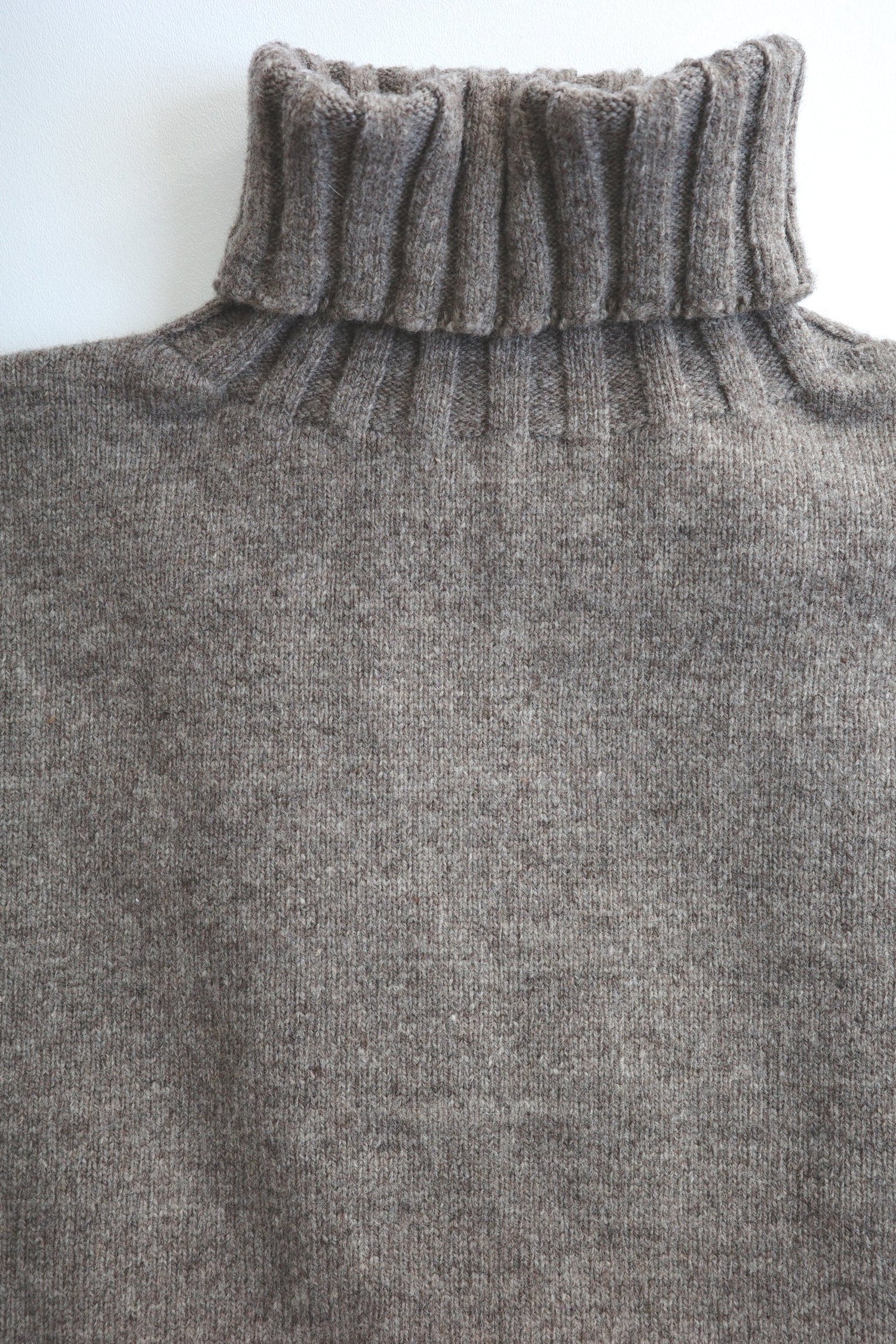 Close up image of a turtle neck sweater with ribbing detailing
