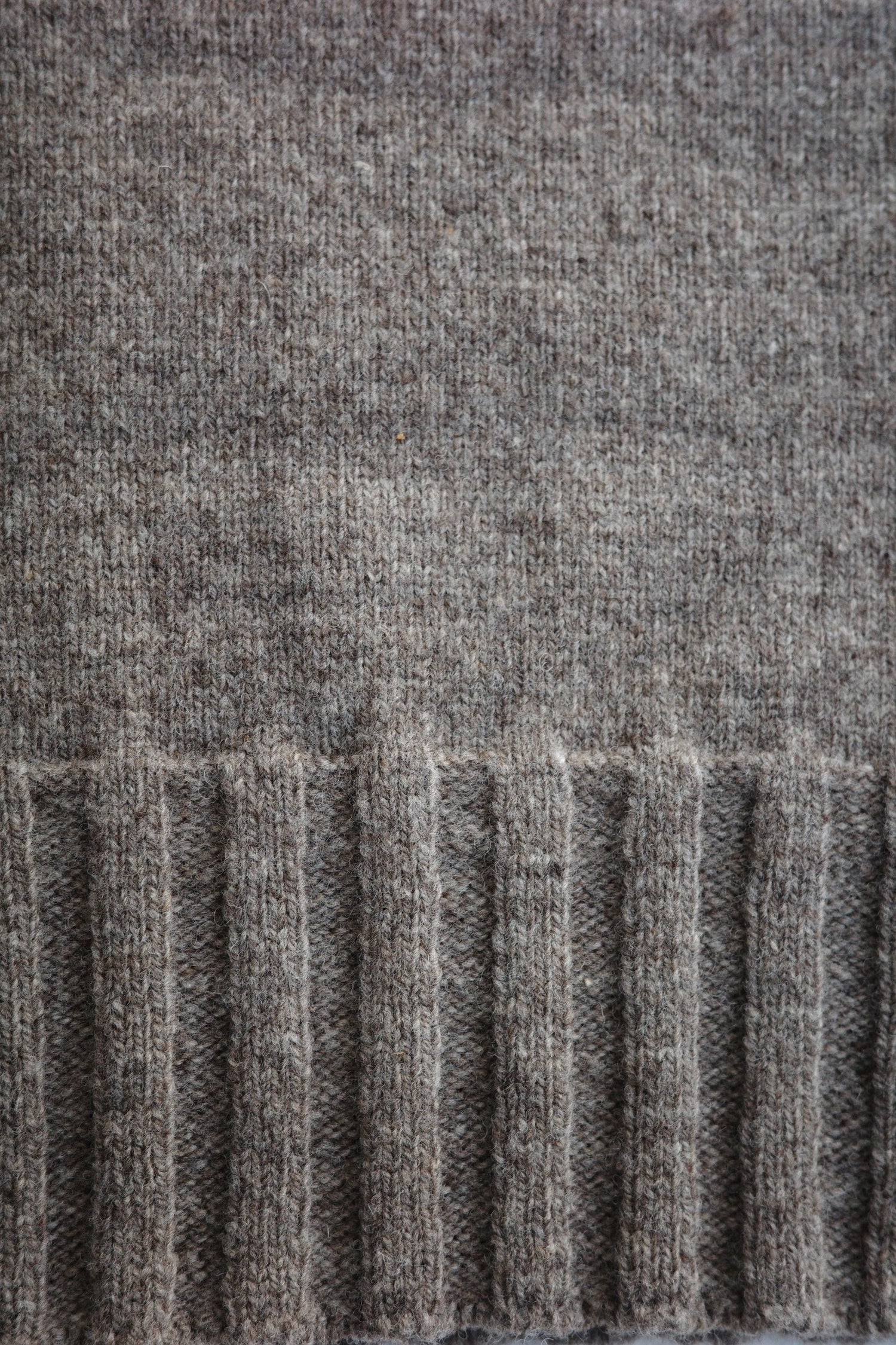 Rib detailing on the bottom of a grey sweater.