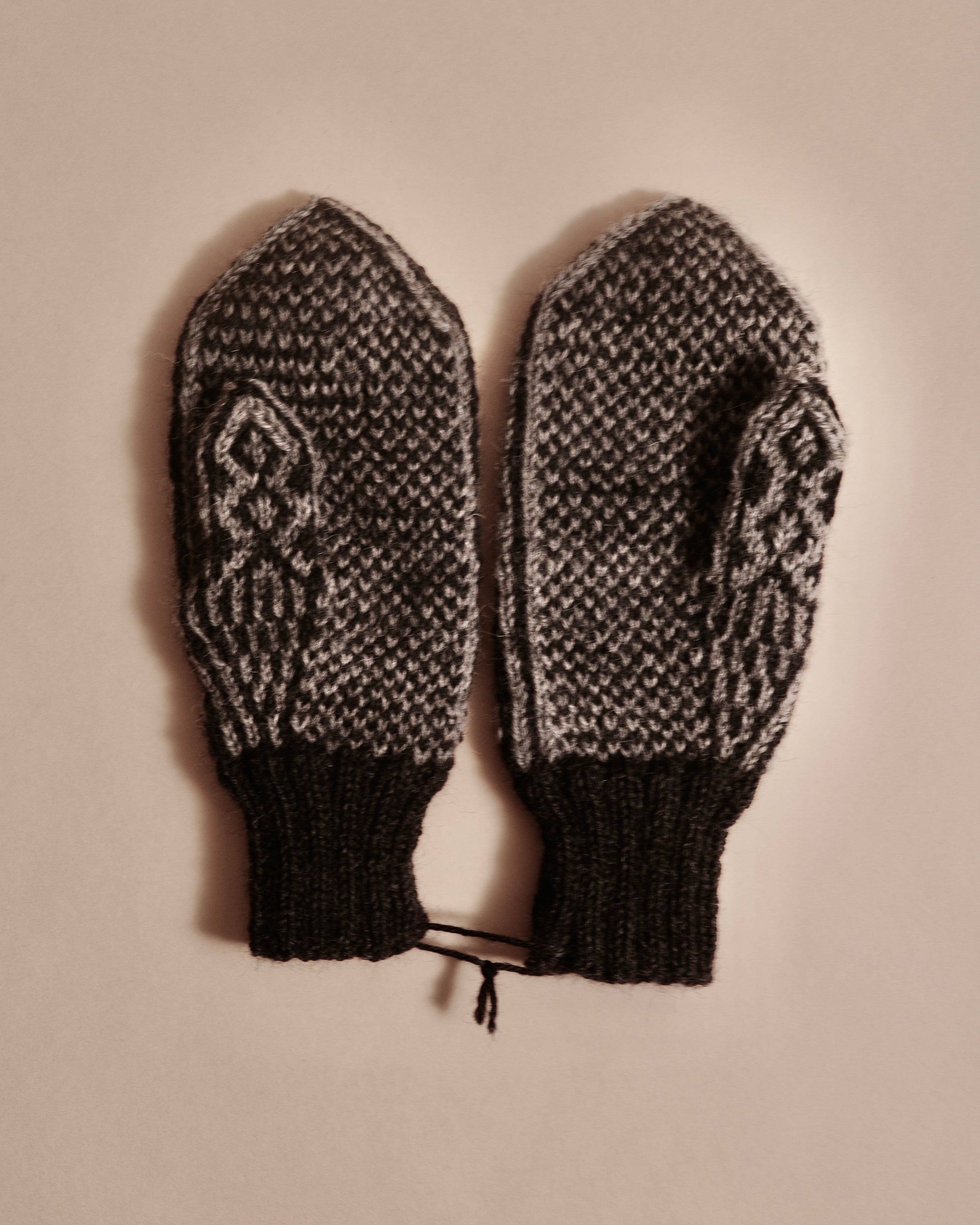 Pair of knitted mittens with a decorative pattern on a beige background