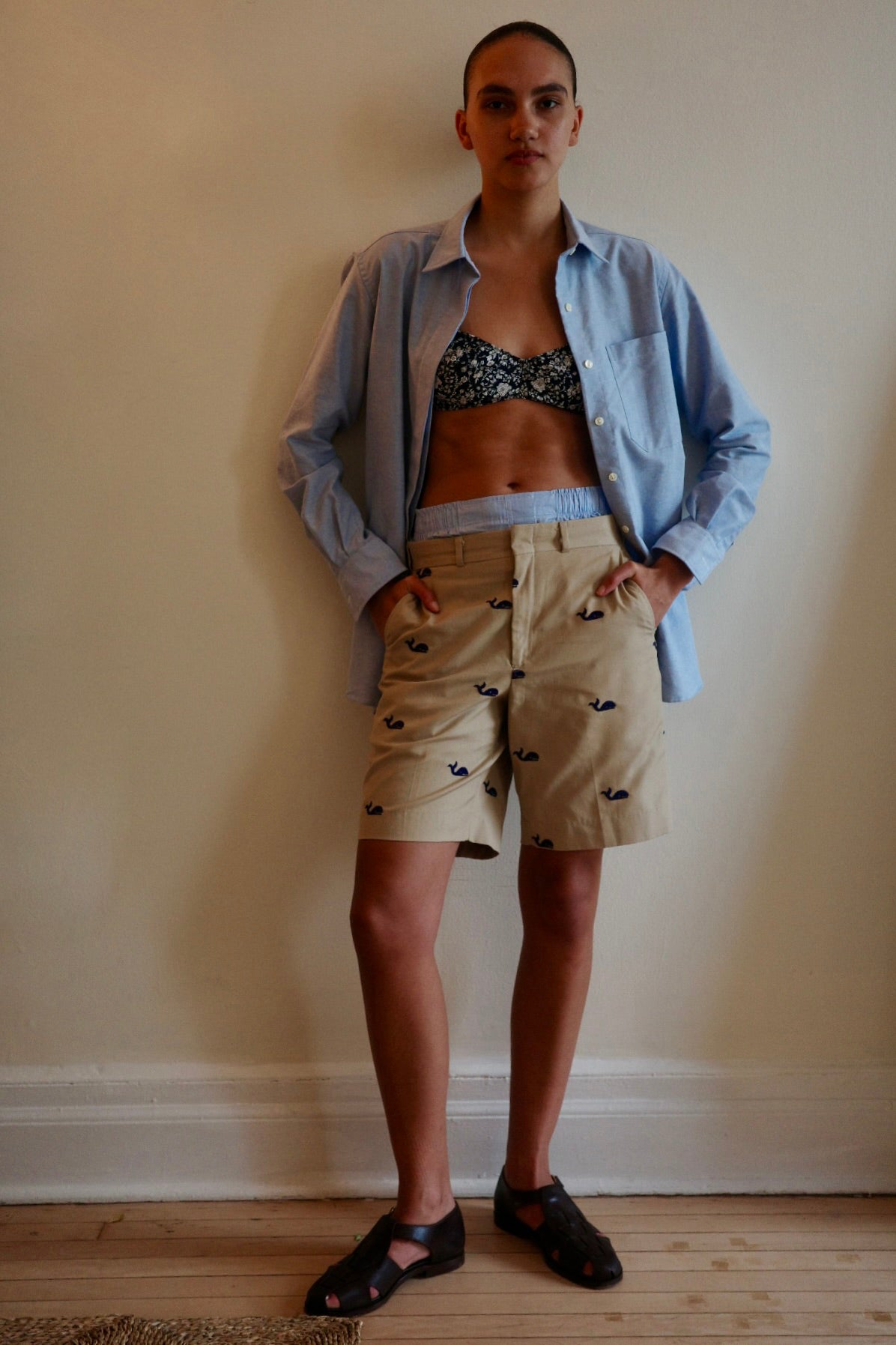 Women standing against wall wearing khaki shorts