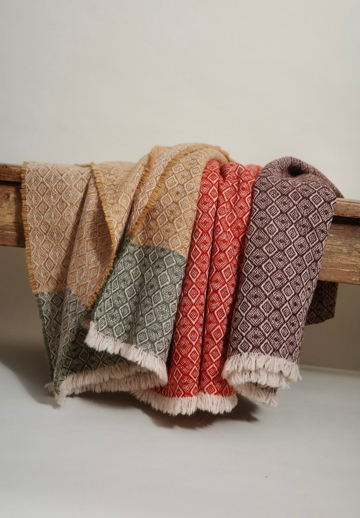 Woven fabric with geometric patterns draped over a wooden rod on a neutral background