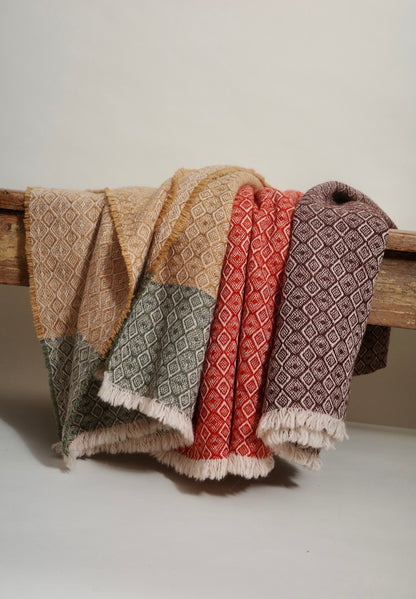 Woven fabric with geometric patterns draped over a wooden rod on a neutral background