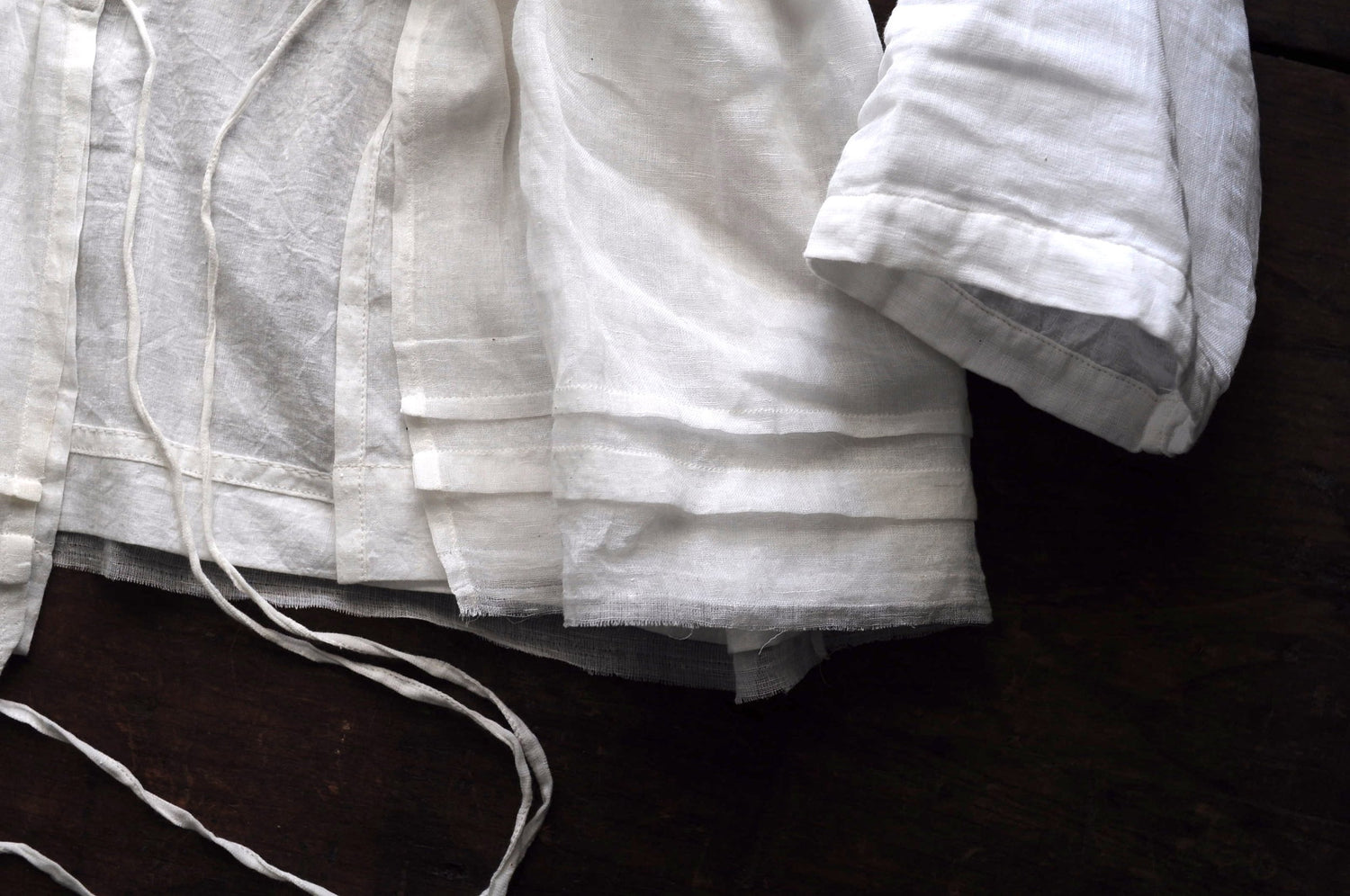 Close up image of the bottom hem a chemise top featuring french pleating and frayed edging.