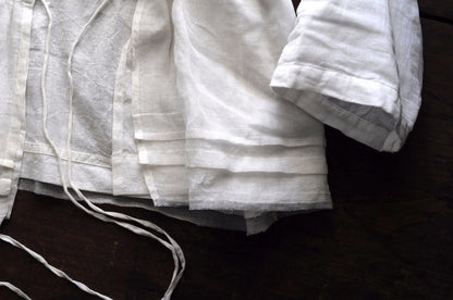 Close up image of the bottom hem a chemise top featuring french pleating and frayed edging.