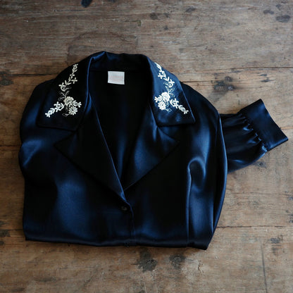 A black silk shirt folded on top of a wooden table.