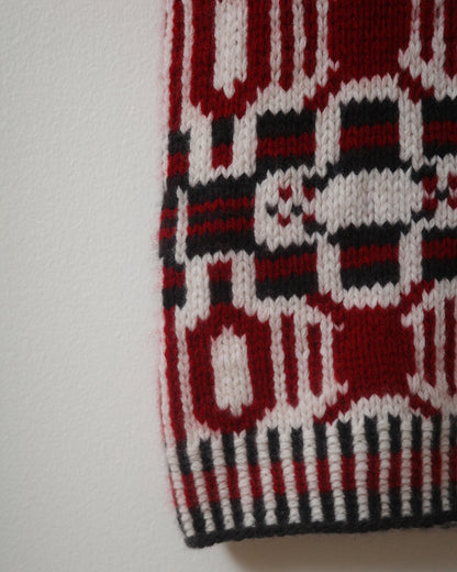 Close-up of a knitted fabric with red, black, and white pattern on a white background