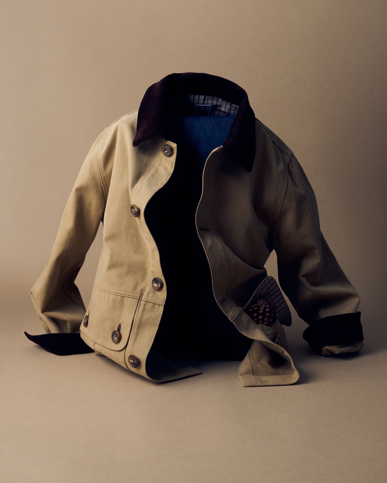 A tan jacket propped upright in front of a beige bakground.