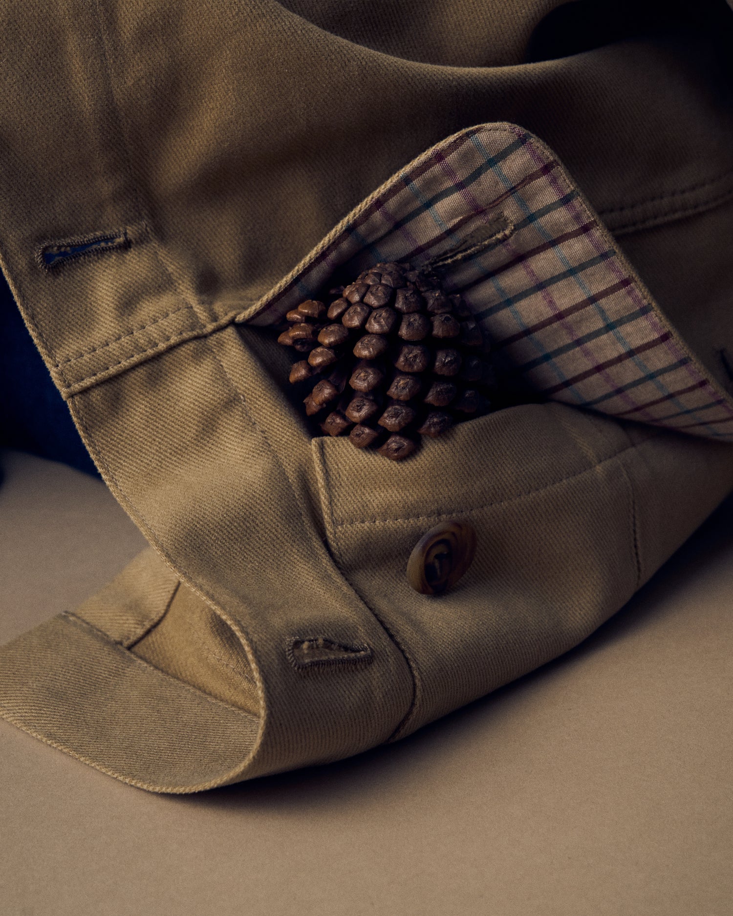 Close up image of a pocket lined in plaid fabric with a pinecone peeking out.