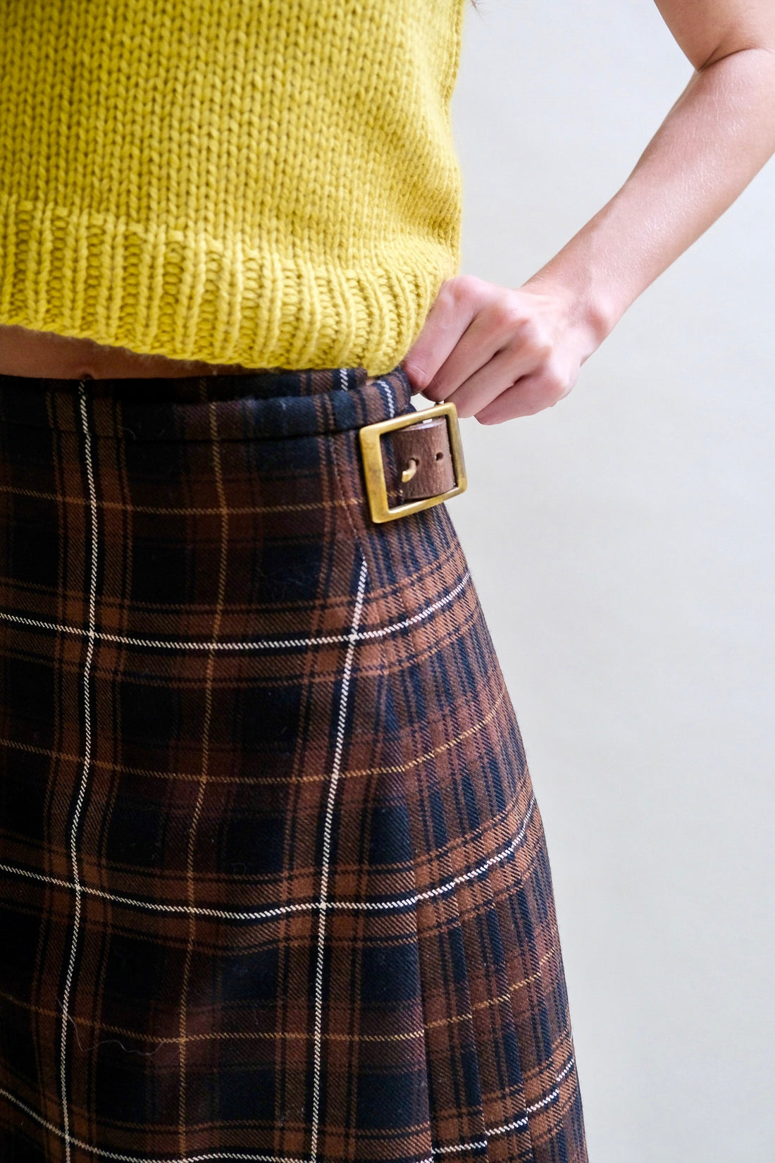 Close up of a black and brown kilt showing leather buckle detailing on side hip.