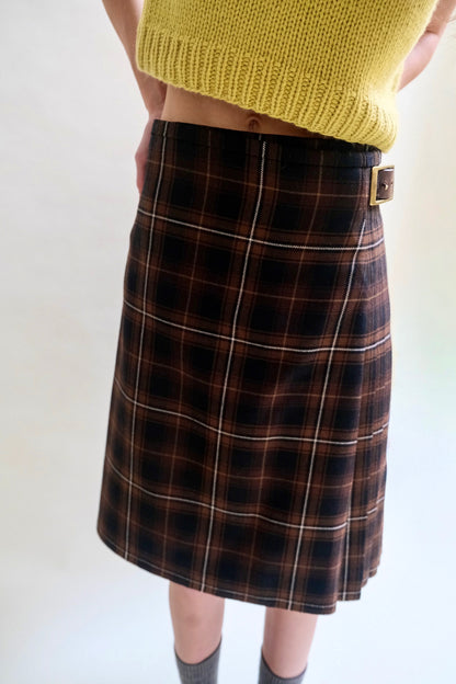 Close up image of a black and brown tartan kilt paired with a chartreuse sweater vest.